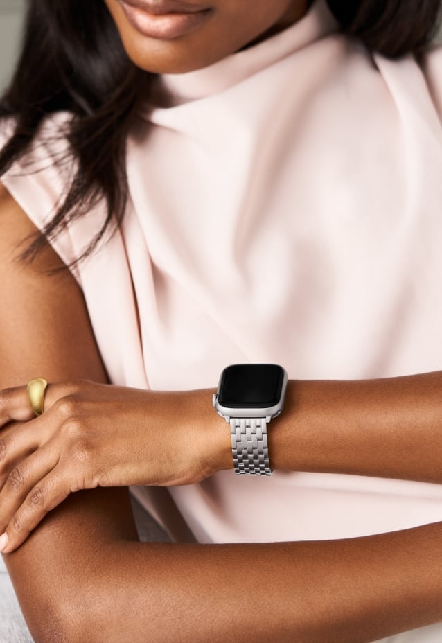 A woman in a light pink blouse wearing the Stainless Steel Bracelet Band for Apple Watch®