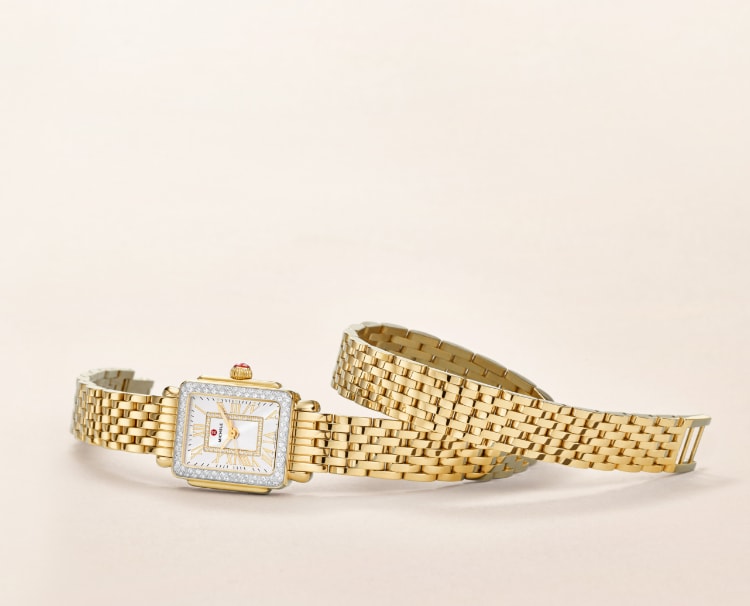 Deco Madison Mini watch in 18k gold features a mother-of-pearl dial with gold Roman numeral indexes, diamond-covered bezel and 18k gold seven-link double-wrap bracelet.