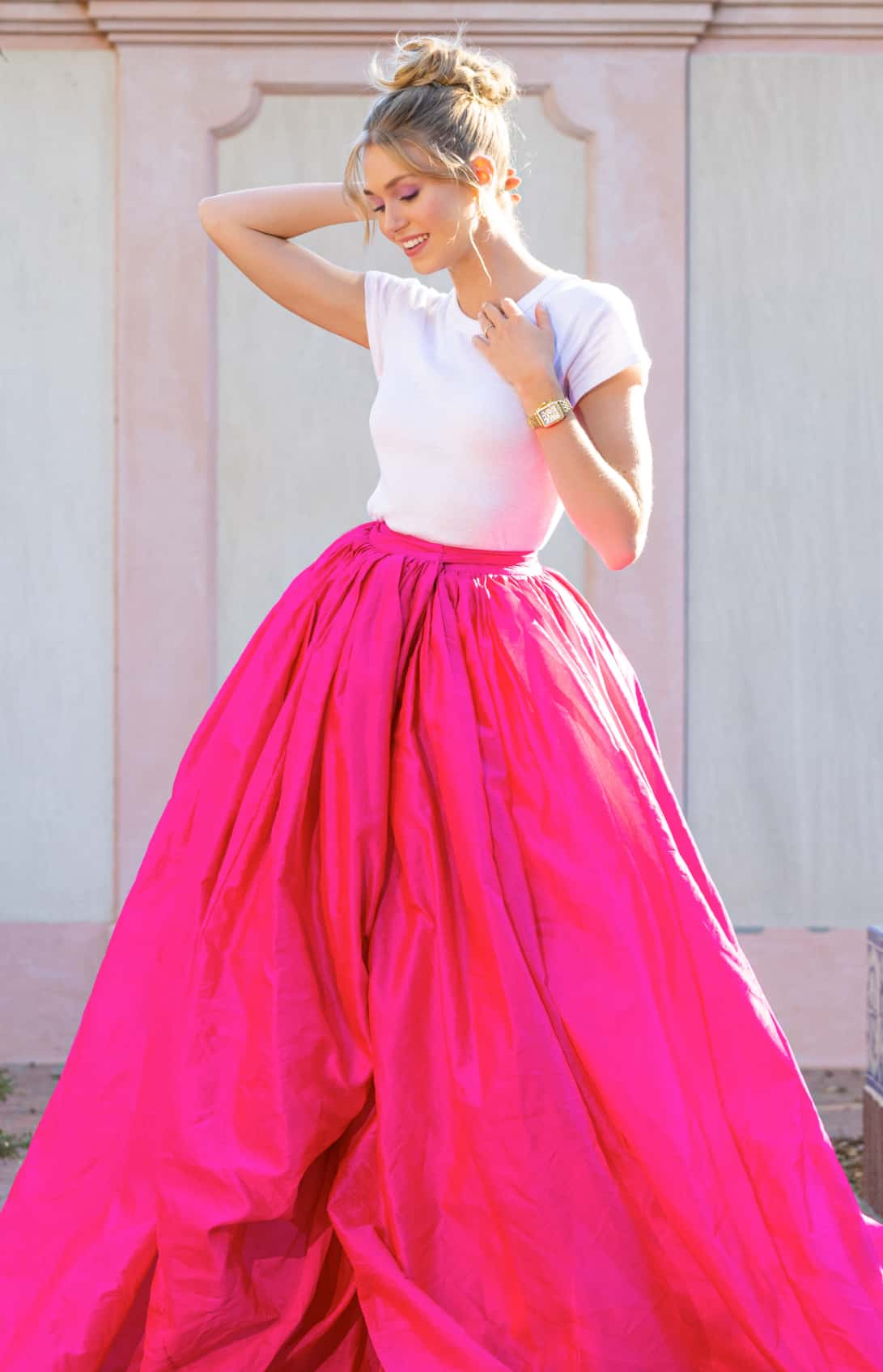 Woman wearing a white tee and a hot pink ball gown skirt wearing a MICHELE watch