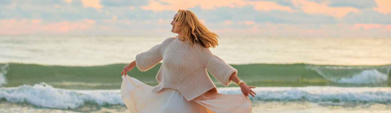 Sophisticated woman twirling along a beach wearing the Deco watch in stainless.