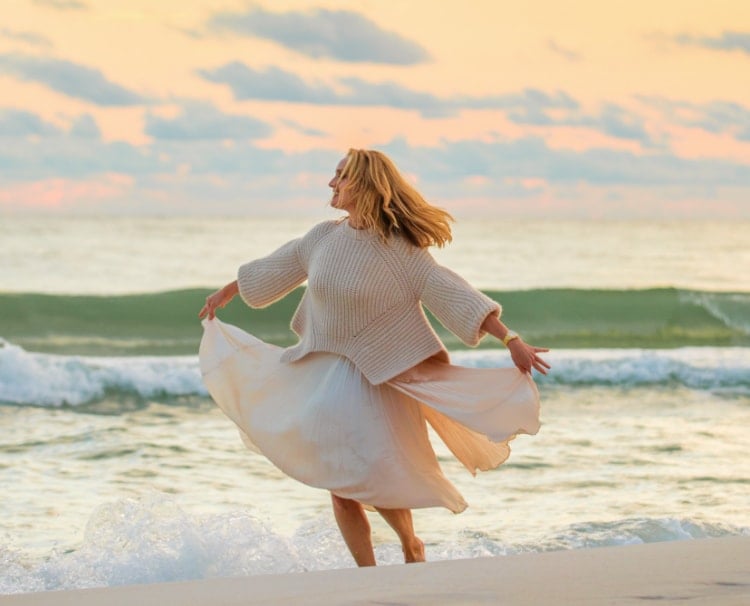Sophisticated woman twirling along a beach wearing the Deco watch in stainless.