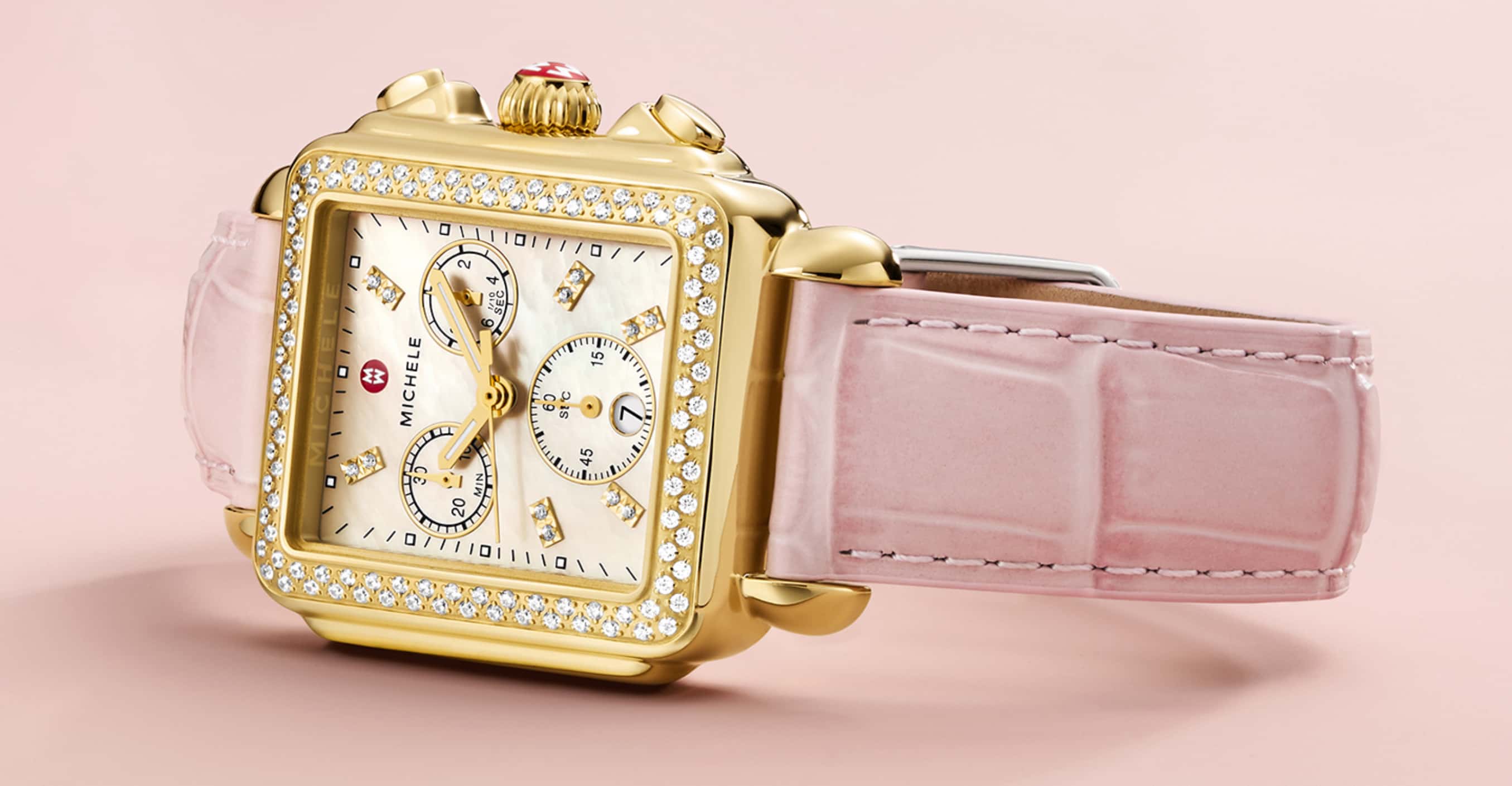 Image of a gold Michele watch with a pink strap.