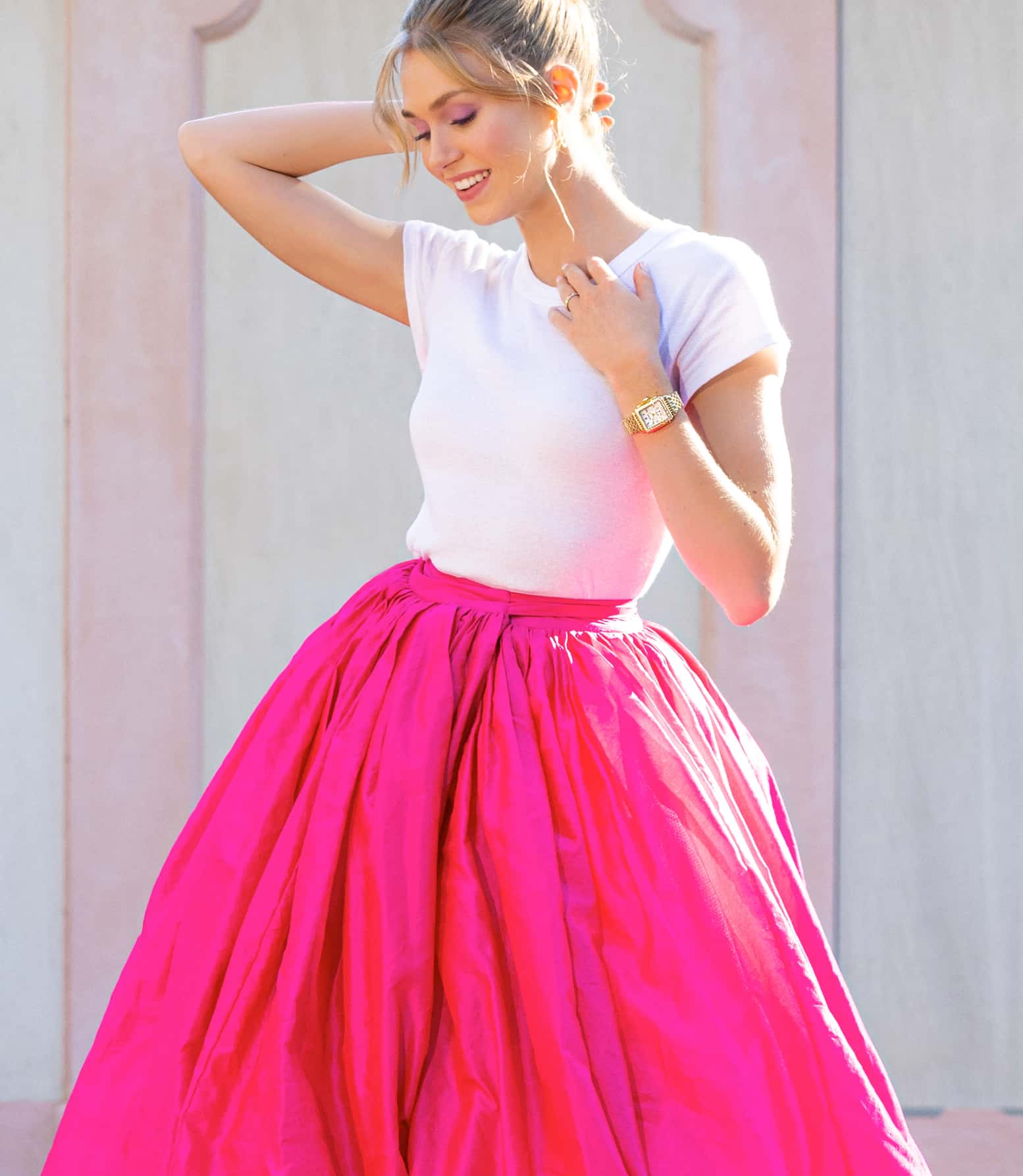 Woman in white tee and pink skirt wearing a MICHELE watch