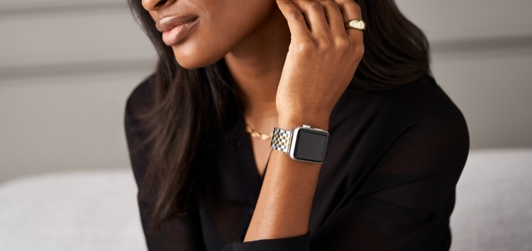 A woman wearing the two-tone 18K gold plated bracelet and diamond case for Apple Watch®