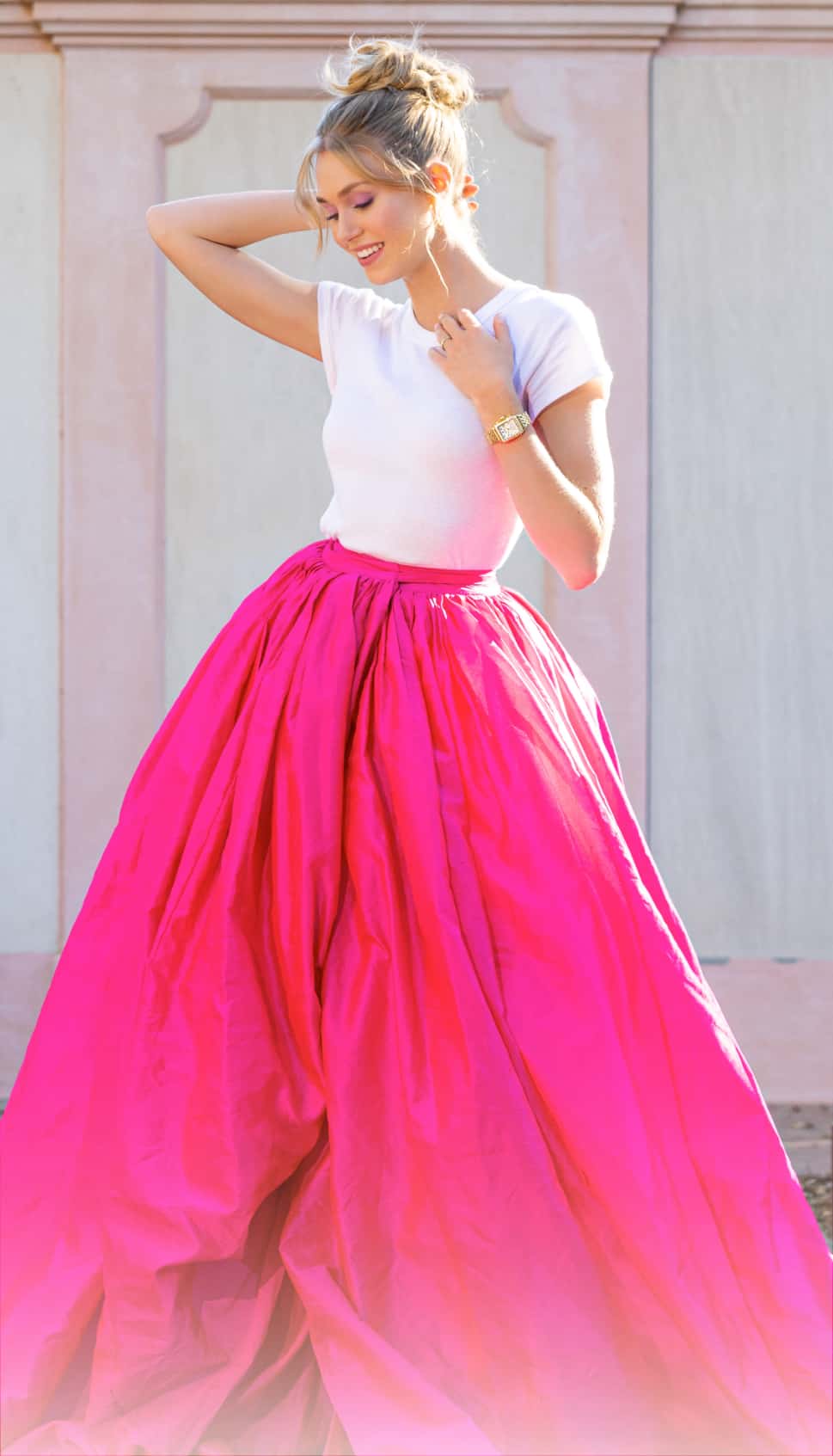 Woman wearing a hot pink skirt and white tee shirt.