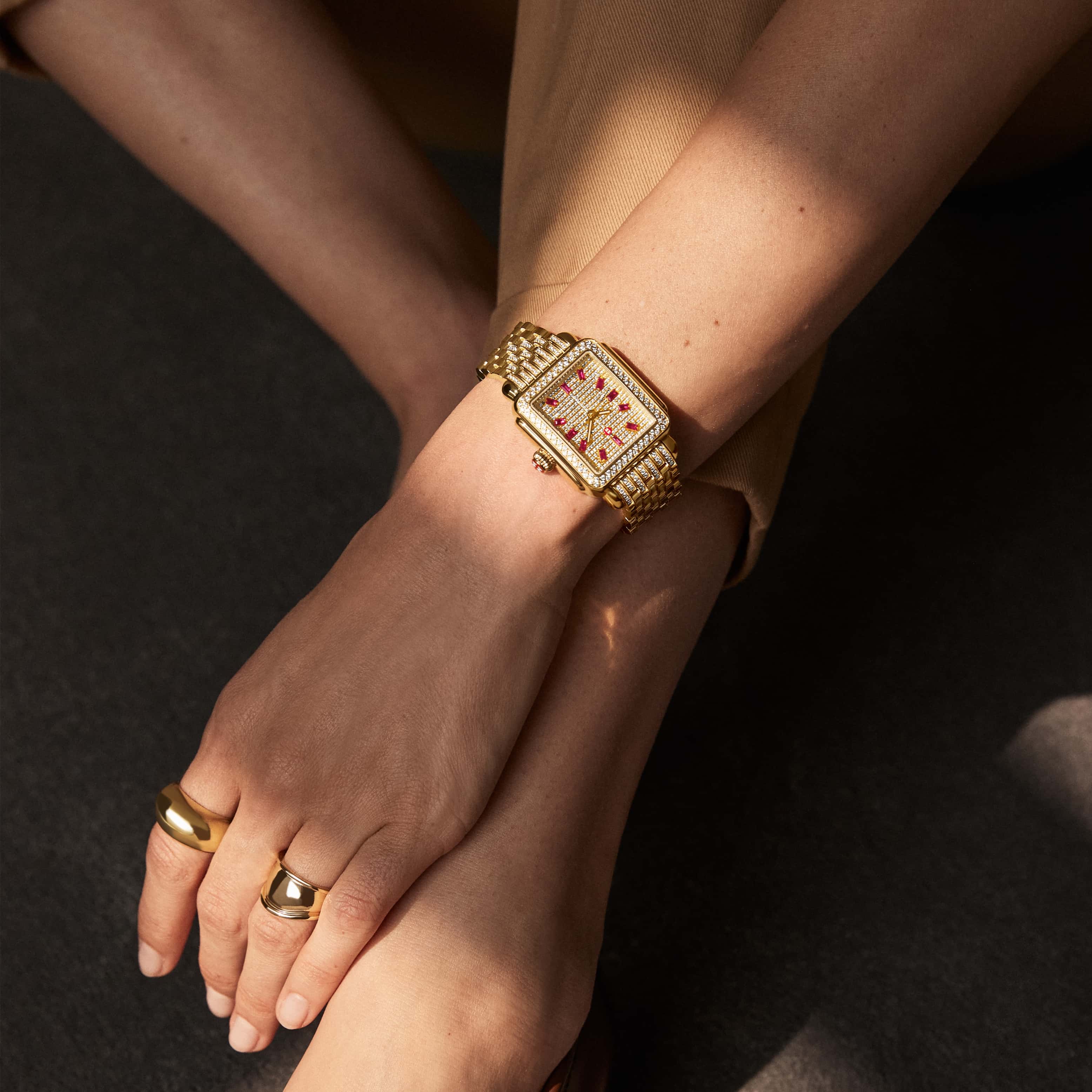 Woman wearing Deco Ruby Pavé watch in all-over gold and diamonds with 12 ruby baguettes